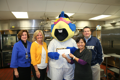 (Caption:) Paying a visit to the Trenton Area Soup Kitchen (TASK) along with Boomer, the Trenton Thunder mascot, are, from left, Patricia Hartpence, Assistant Vice President for Corporate Giving, NJM Insurance Group; Cindy Berger, NJM's Community Outreach Events Coordinator; and Will Smith, General Manager and Chief Operating Officer of the Thunder. Boomer hands NJM's donation check to Xiumei Chen, Manager of Finance and Administration for TASK.